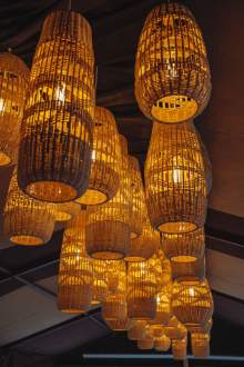 Suspensions lumineuses en osier à l’intérieur de La Cabane Meudon, restaurant chaleureux au cœur de la forêt à Meudon