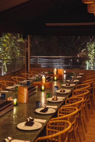 Grande table dressée sur la terrasse couverte de La Cabane Meudon, restaurant en forêt adapté aux repas de groupe et événements à Meudon