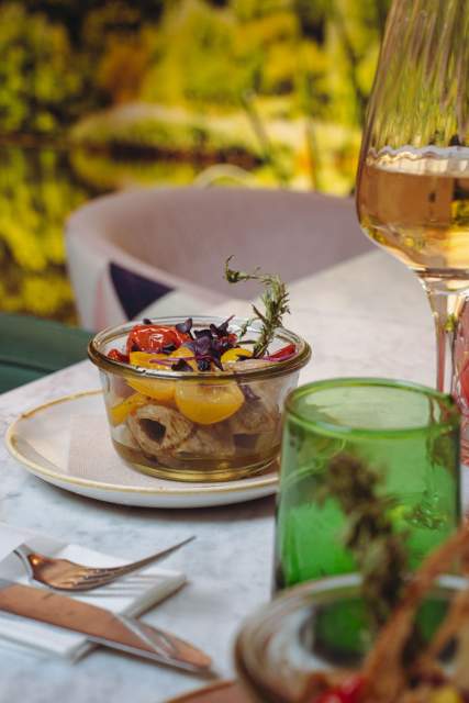 Assiette de plat mijoté aux légumes colorés servie sur table en marbre vert du restaurant La Cabane Meudon, accompagnée d’un cocktail vert au citron vert dans un verre à pied à Meudon