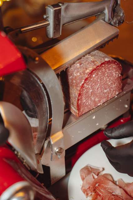 Fines tranches de jambon à la trancheuse rouge, dressées dans une assiette blanche au restaurant à Meudon