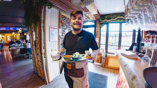 Serveur de La Cabane Meudon portant des plats à table, restaurant convivial en pleine nature à Meudon
