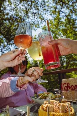 Clients trinquant avec des boissons sur la terrasse de La Cabane Meudon, restaurant en pleine nature avec vue sur le lac de Meudon