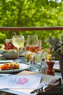 Table dressée sur la terrasse de La Cabane Meudon avec plats et verres de vin, restaurant en pleine nature à Meudon
