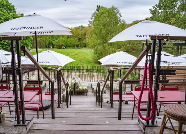 Espace lounge sur la terrasse de La Cabane Meudon avec parasols rouges, restaurant en forêt à Meudon