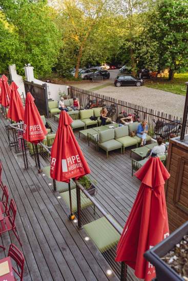 Espace lounge sur la terrasse de La Cabane Meudon avec parasols rouges, restaurant en forêt à Meudon
