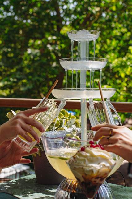 Clients se servant une boisson à la fontaine sur la terrasse de La Cabane Meudon, restaurant en pleine nature à Meudon