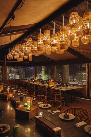 Salle chaleureuse de La Cabane Meudon éclairée par des suspensions en osier, restaurant en forêt à Meudon