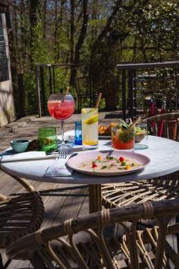 Table dressée sur la terrasse de La Cabane Meudon avec plats et cocktails, restaurant en pleine nature à Meudon