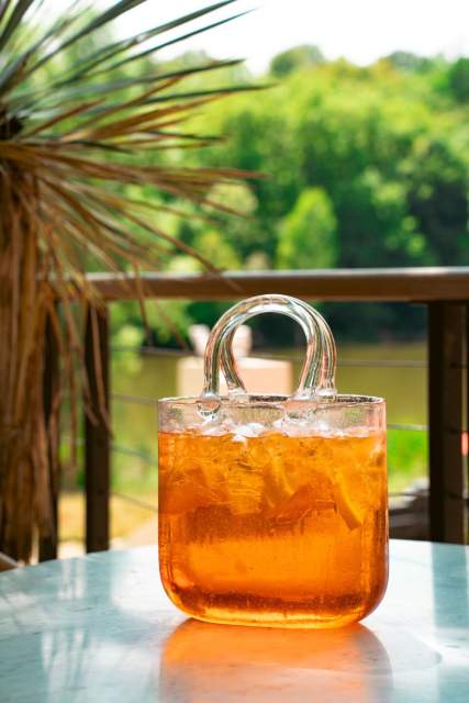 Clients se servant une boisson à la fontaine sur la terrasse de La Cabane Meudon, restaurant en pleine nature à Meudon