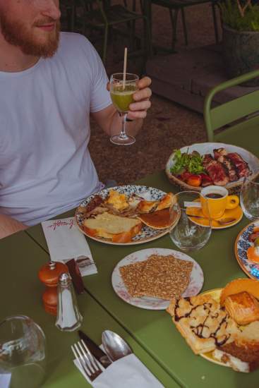 Groupe d’amis déjeunant sur la terrasse de La Cabane Meudon sous des parasols rouges, restaurant convivial en forêt à Meudon