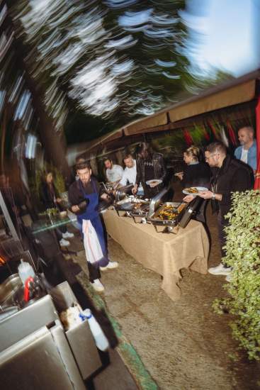 Équipe en pleine action autour d’un buffet barbecue en extérieur à La Cabane Meudon, avec grillades et plats chauds servis sur la terrasse en soirée
