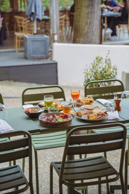 Clients se servant une boisson à la fontaine sur la terrasse de La Cabane Meudon, restaurant en pleine nature à Meudon