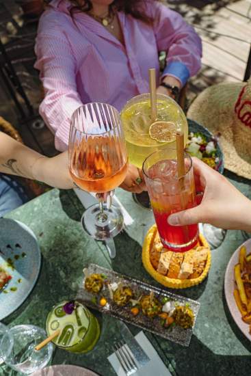 Clients trinquant avec des cocktails sur la terrasse de La Cabane Meudon, restaurant convivial en pleine nature à Meudon