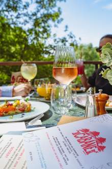 Table dressée sur la terrasse de La Cabane Meudon avec plats et verres de vin, restaurant en pleine nature à Meudon
