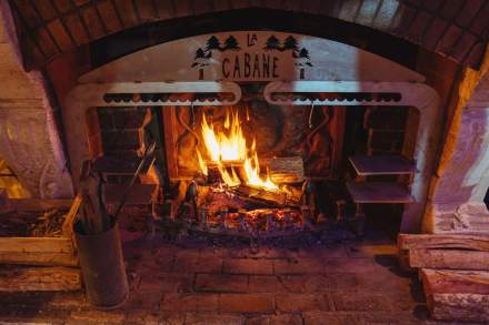 Cheminée allumée à l’intérieur de La Cabane Meudon, restaurant chaleureux en forêt idéal pour les soirées d’hiver à Meudon